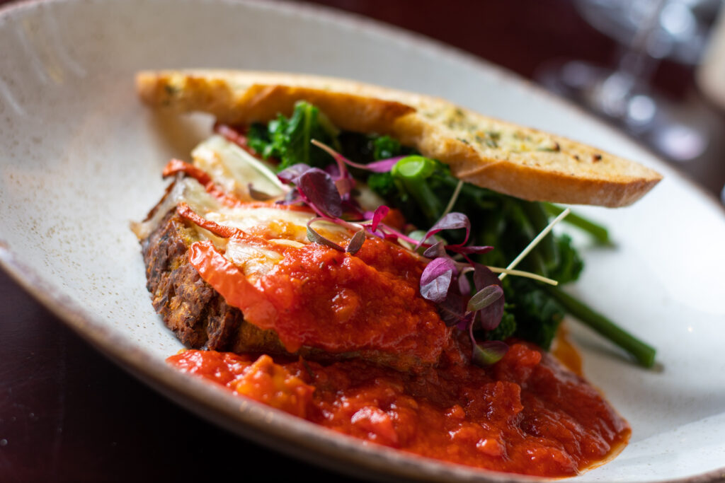 A close up of a plate of food, with some tomato-based sauce on some sourdough bread